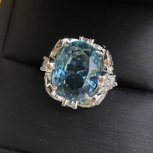 Macro shot of large oval blue gemstone ring with intricate silver floral settings in box