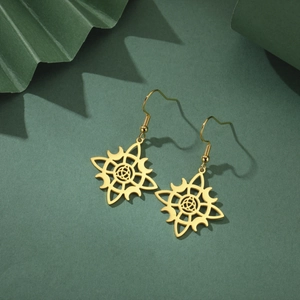 Close-up of golden stainless steel hollow witch knot moon pendant earrings on dark green