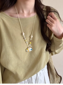 Detail of seashell pendant necklace and gold ring styled for a summer vacation look