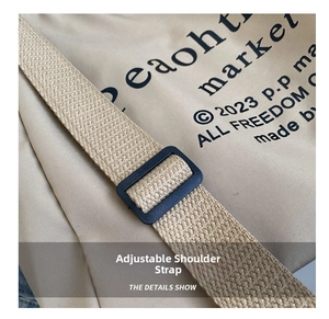 Detail of adjustable wide shoulder strap and black plastic buckle on beige canvas tote bag