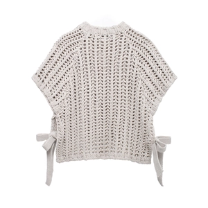 Gros plan du gilet en maille beige avec nœuds latéraux et détails ajourés