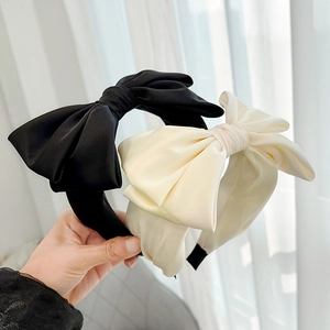 Detail view of black and beige satin headbands with large elegant bow accents