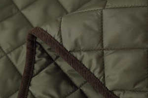 Détail du tissu matelassé losange vert olive avec bordure en velours côtelé brun