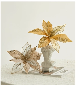 Detail of glittered champagne artificial flowers with sequins on a white textured surface