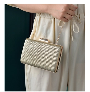 Detailed view of gold pleated clutch bag with metal chain strap and rectangle clasp