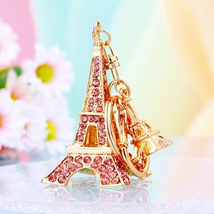 Close-up of golden Eiffel Tower keychain with pink rhinestones on a floral background