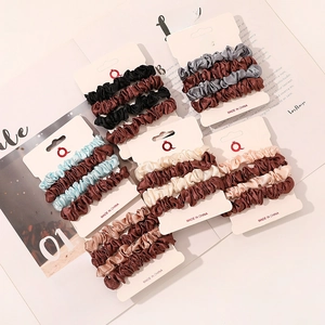 Detail of satin scrunchie sets in assorted earthy tones on decorative book background
