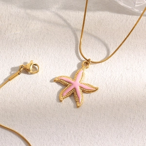 Close-up of golden necklace with pink starfish pendant and smooth snake chain detail