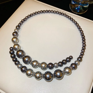 Detail of grey gradient faux pearl necklace with vintage silver spacers on white leather