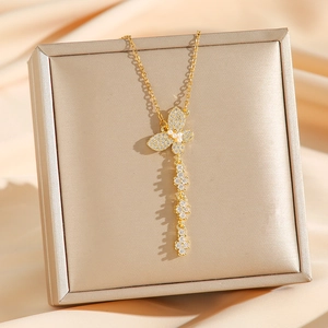Elegant gold butterfly tassel necklace with pavé zircon and pearls on a silk background
