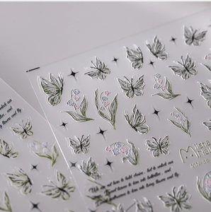 Macro shot of 3D embossed silver butterfly and flower nail art stickers with metallic texture