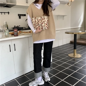 Gros plan d'une pochette fleurie en velours côtelé avec gilet beige et jean denim