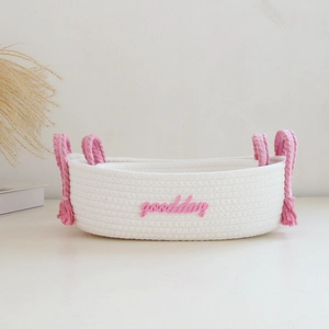 Detail of hand-woven white cotton rope basket with pink handles and goodday lettering
