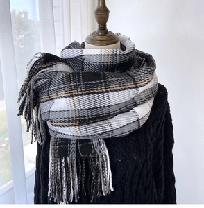 Detail of plaid scarf featuring soft cashmere-like texture and delicate fringe edges
