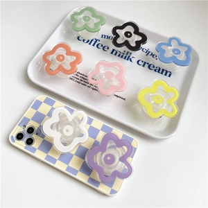Flat lay of colorful flower shaped phone grips on checkerboard case and tray