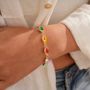 Close-up of a golden bracelet with colorful oval resin stones worn on a wrist