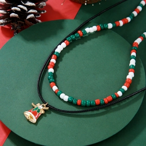 Close-up of a double-layered Christmas necklace with gold bell pendant and festive beads