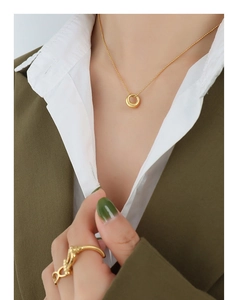 Detail of a minimalist gold oval pendant necklace paired with a matching ring and chic outfit