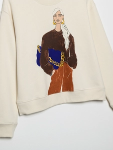 Detail of cream sweatshirt featuring stylish female graphic print and ribbed cuffs