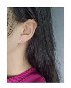 Detailed close-up of S925 sterling silver heart-shaped knot stud earrings on a model's ear