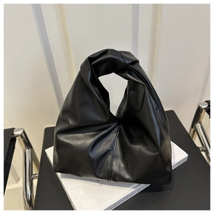 Detail view of black faux leather tote with knotted handle and pleated texture design
