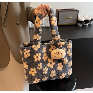 Detail of plush tote bag with yellow sun flower pattern and cute fur ball accessory
