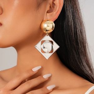 Close-up of geometric gold and silver mixed metal earrings worn on a model's ear