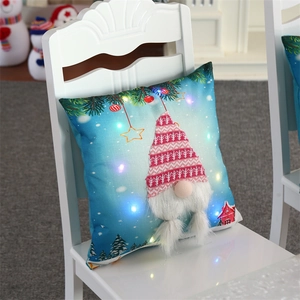 Close-up of LED glowing Christmas gnome pillow with 3D plush beard on white chair