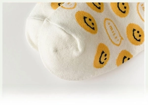 Detail of soft seamless toe and yellow smiley face pattern on white cotton socks