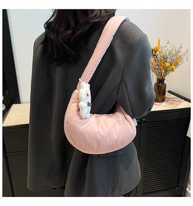 Détail du sac dumpling rose rembourré avec charme lapin porté par un mannequin en blazer
