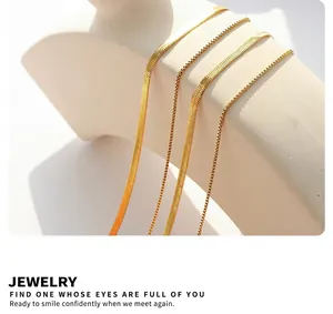 Close-up of double-layered gold snake chain necklaces on a minimalist beige display