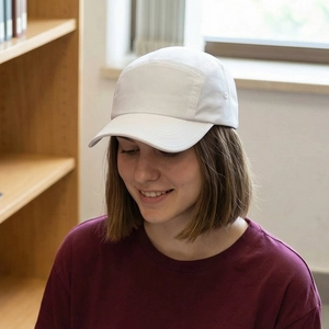 White minimalist five-panel camping cap worn by a male model in a cozy indoor setting