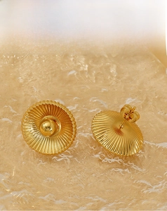 Macro detail of gold vintage stud earring with radial pleated texture and central bead
