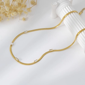 Detailed view of gold snake chain necklace with rectangular zirconia on white background