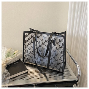Detail of large tote bag featuring black and white monogram pattern on silver stand