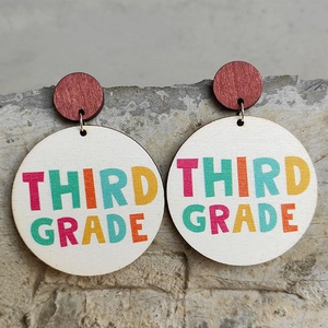 Macro detail of wooden Third Grade earrings with colorful letters on stone surface