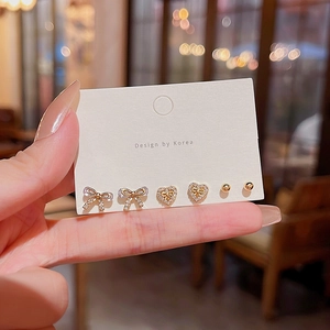 Three-piece gold earring set with rhinestone bow, heart, and ball studs on display card