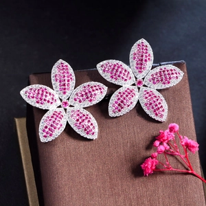 Close-up of pink and white zircon flower earrings on brown silk jewelry box