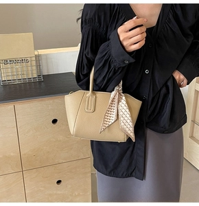 Close-up of beige lychee textured bucket bag with a geometric pattern silk scarf handle