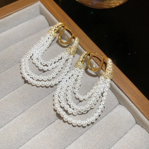 Vue détaillée des boucles d'oreilles logo CD doré avec franges de perles multicouches
