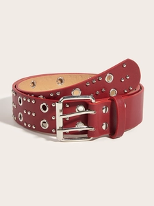 Detail view of red punk leather belt featuring silver metal eyelets and double prong buckle
