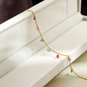 Close-up of 18K gold plated chain with colorful zircon gems on a white velvet jewelry box