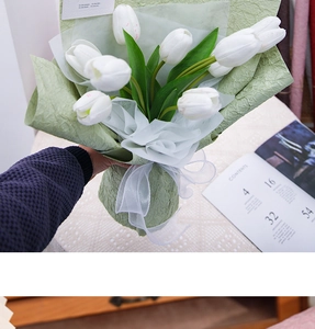Close-up of artificial white tulips wrapped in handmade light green textured crepe paper