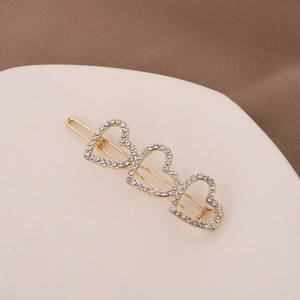 Barrette en alliage doré avec trois cœurs sertis de strass sur plateau rose