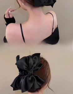 Dettaglio di un grande fermaglio per capelli con fiocco di raso nero e finitura lucida