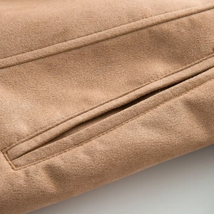 Detail of camel suede jacket showing side pocket stitching and fine fabric texture