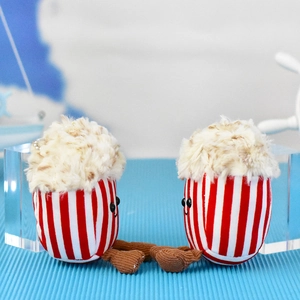 Close-up of two cute popcorn plush doll charms with smiling faces and dangling legs