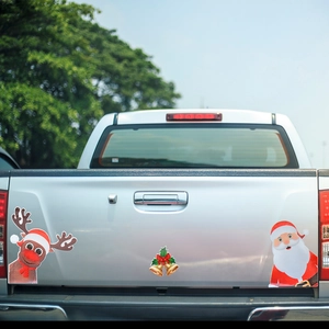 Close-up of reindeer and Santa Claus magnetic reflective stickers on a silver pickup truck