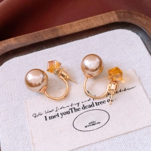 Détail des boucles d'oreilles avec perle champagne et cristal ambré sur carte rétro