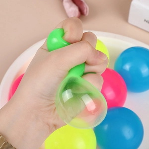 Gros plan d'une main pressant une balle anti-stress verte et collante en TPR souple